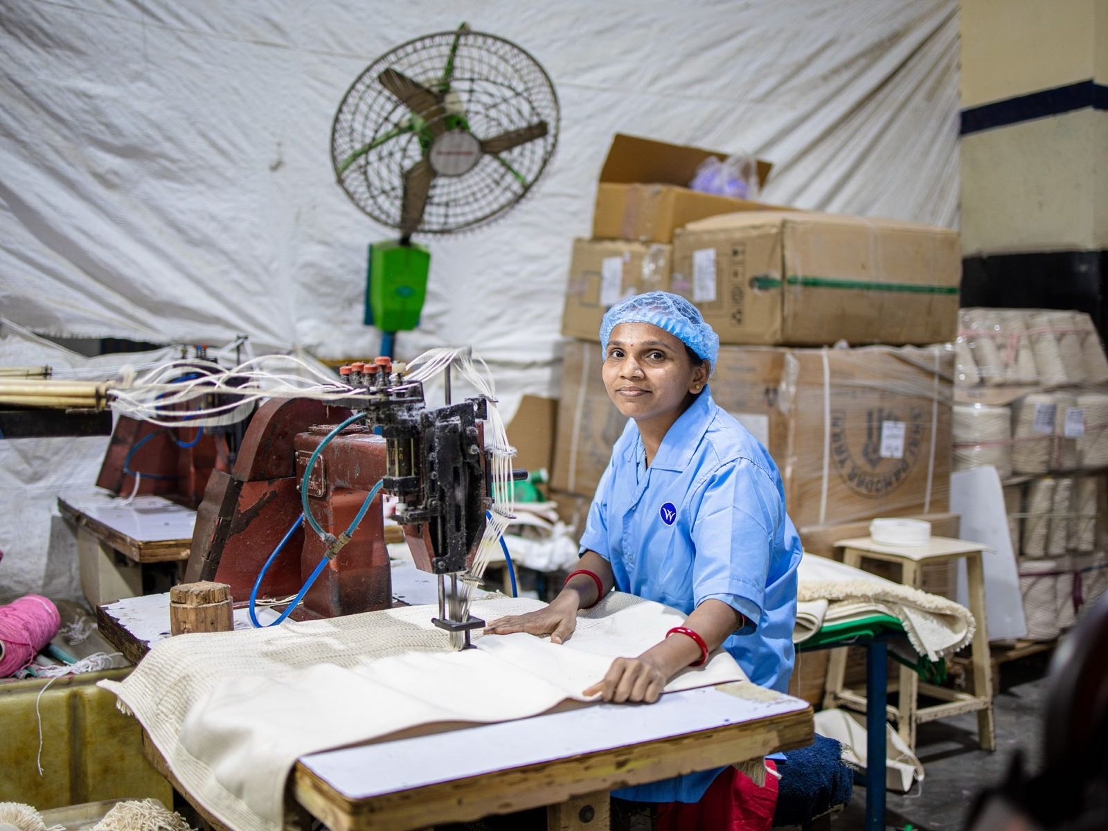 Machine operator sewing fabric on a garment factory floor