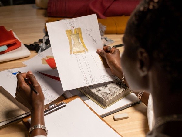 Designer sketching a garment design at a studio desk