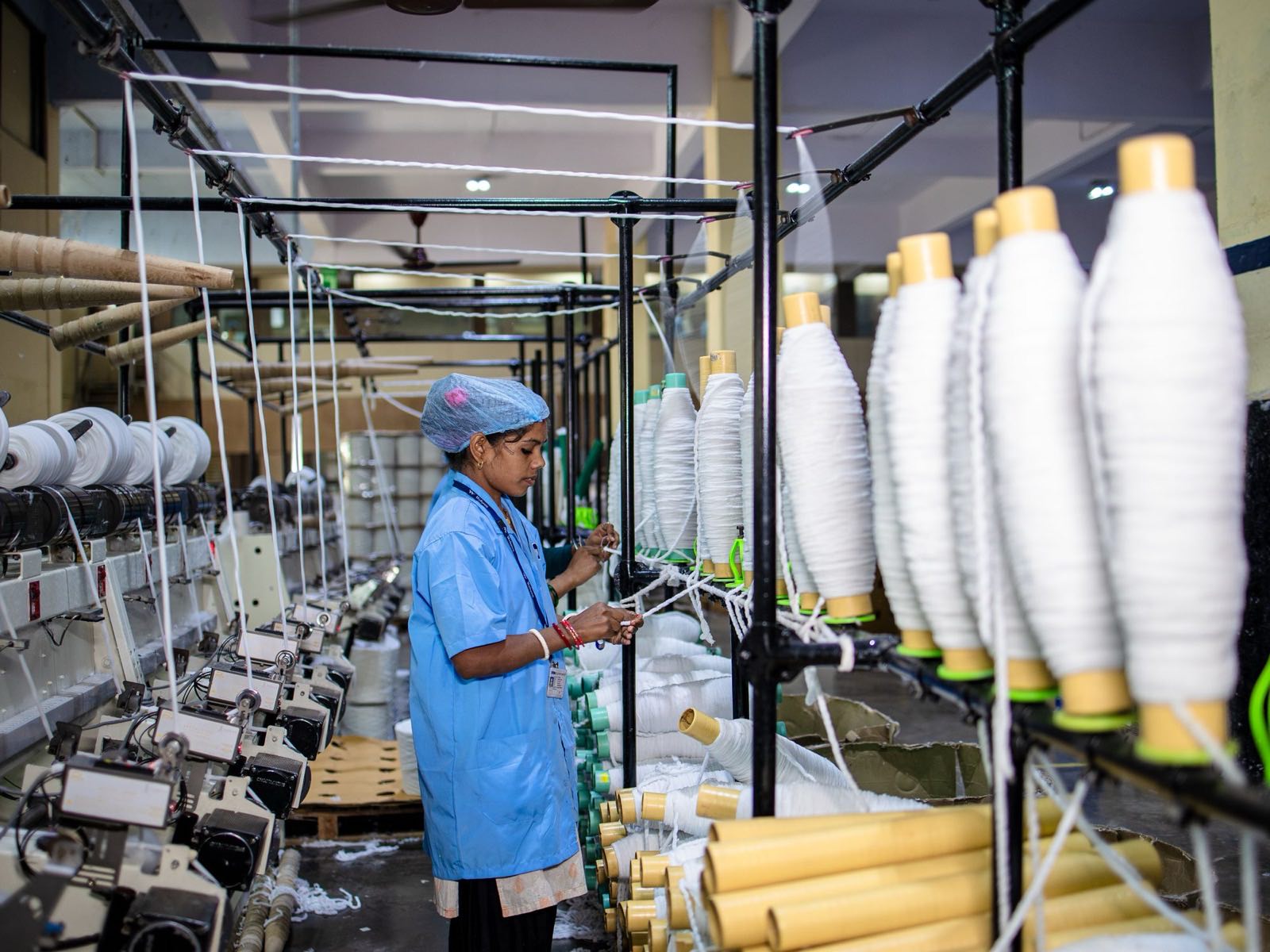 Factory worker operating spinning machinery in a textile mill